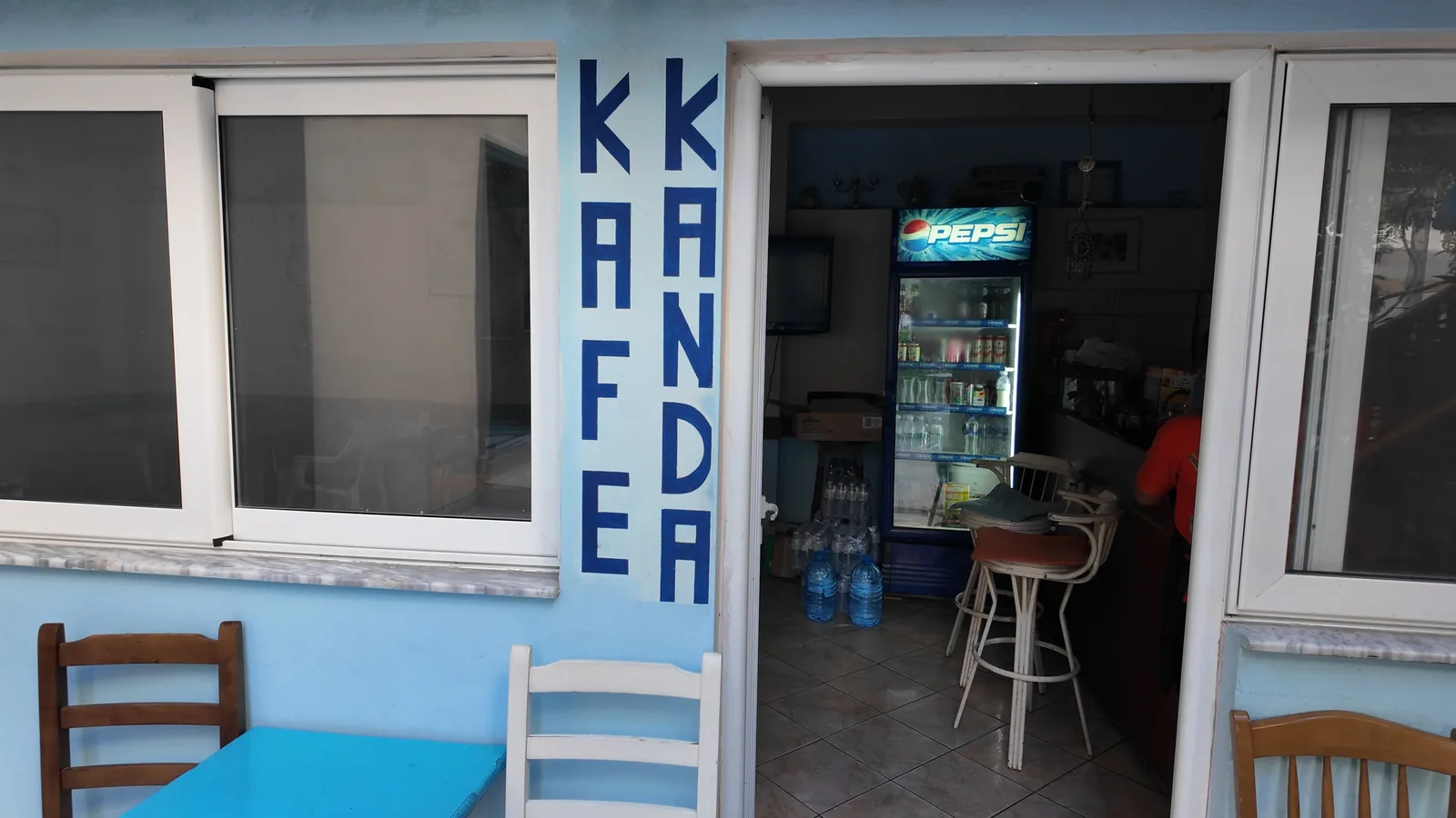 The blue painted front of Cafe Kanda in Himarë, with the name in big letters beside the open door