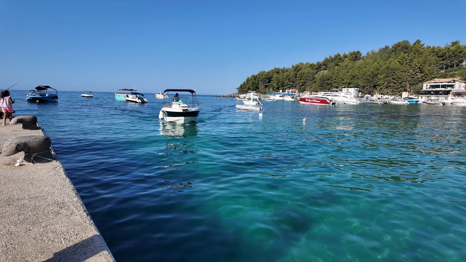 Small motor boats moored in the clear turquoise water of the Himarë harbour