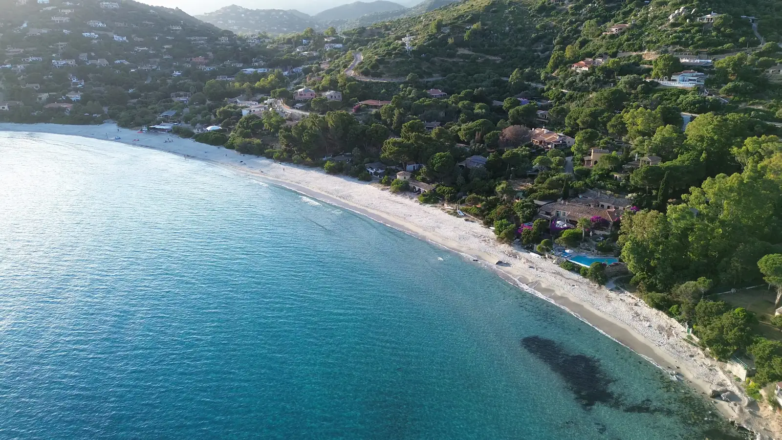 The curved beach and wooded shore at Cala Gonone from the air
