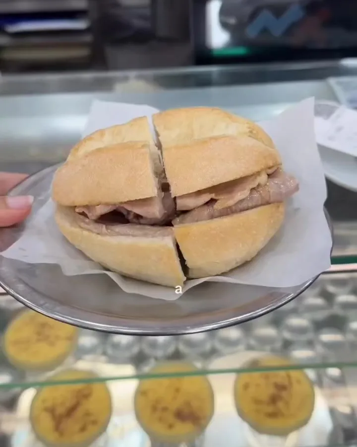 A bifana roll on a plate at the O Trevo counter