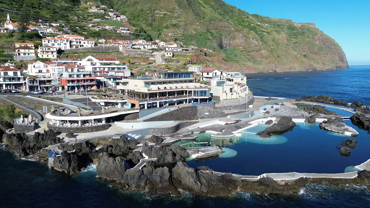 The volcanic rock pools at Porto Moniz from above, with the village and green cliffs behind