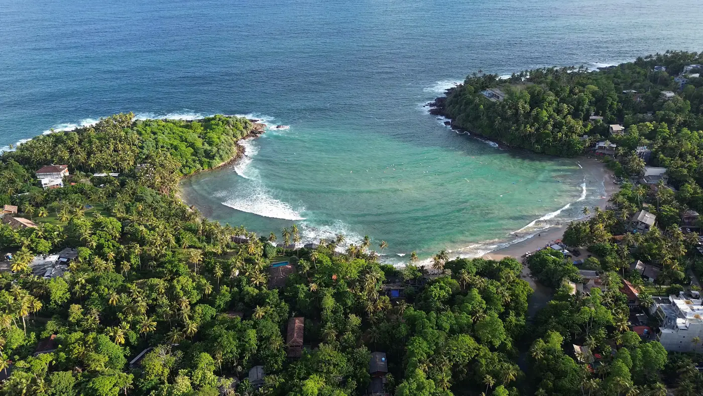 The horseshoe bay at Hiriketiya from the air, ringed by palms and jungle