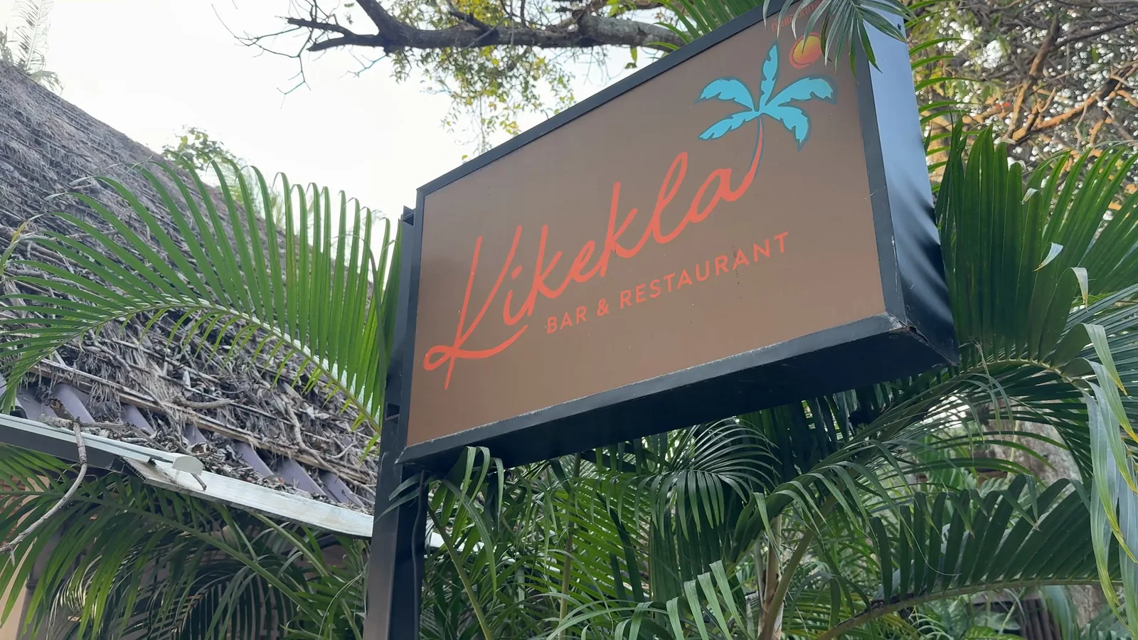 The KikeKla bar and restaurant sign among palm fronds